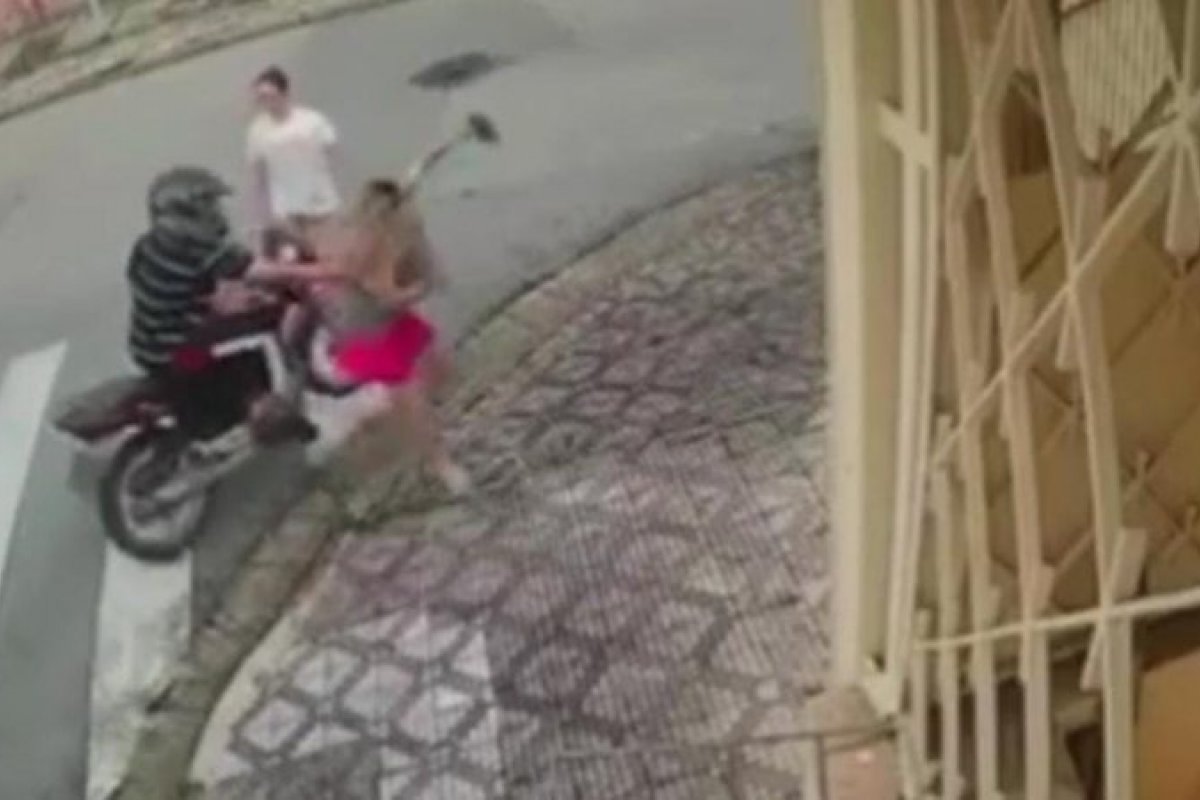 Homem em motocicleta puxa mulher pela camisa durante assalto em Taubaté, interior de SP