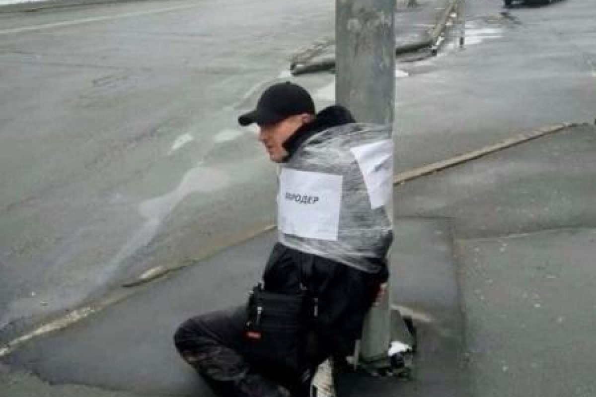 Soldados ucranianos amarram homens em postes após supostos saqueamentos em lojas e casas