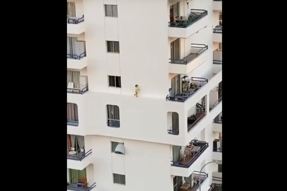 Criança é flagrada tentando atravessar beirada de um prédio