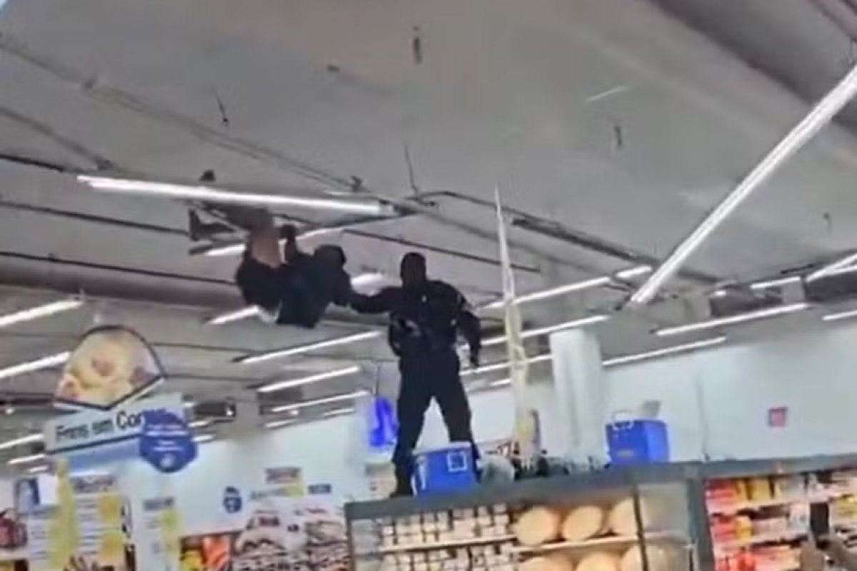 Vídeo: homem se pendura em teto de supermercado e é retirado pela polícia