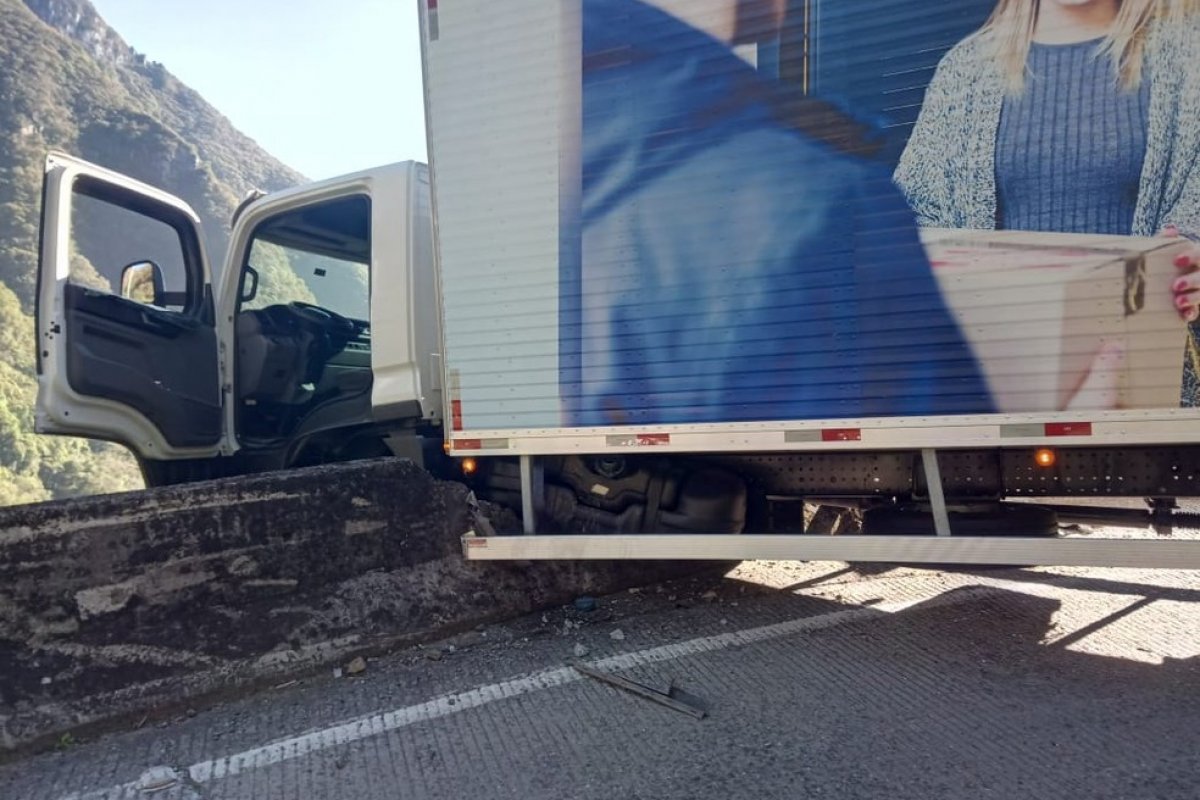 Caminhão bate em mureta e fica pendurado em penhasco 