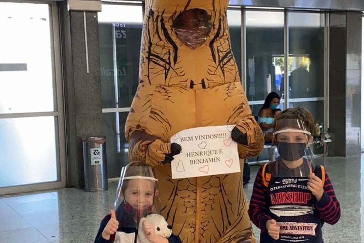 Para se proteger da Covid-19, mãe recepciona filhos em aeroporto fantasiada de dinossauro