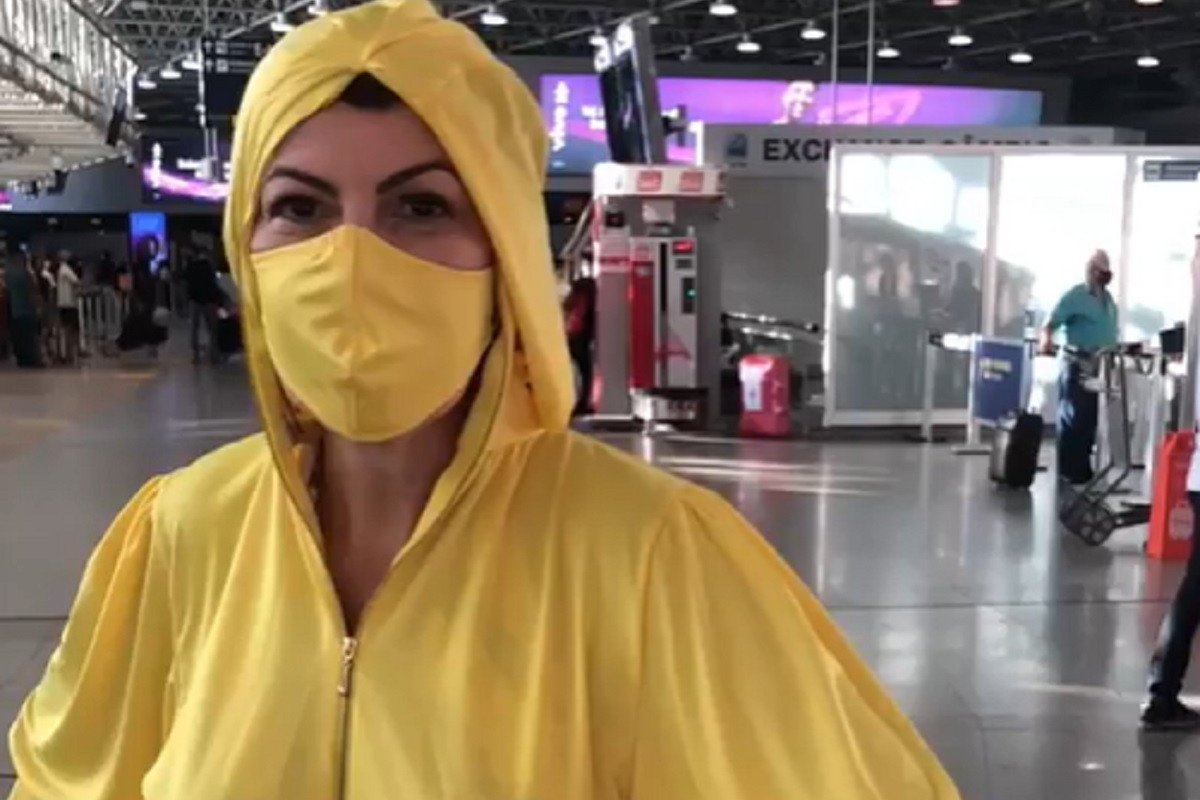Atriz Claudia Lira usa macacão descartável para voo